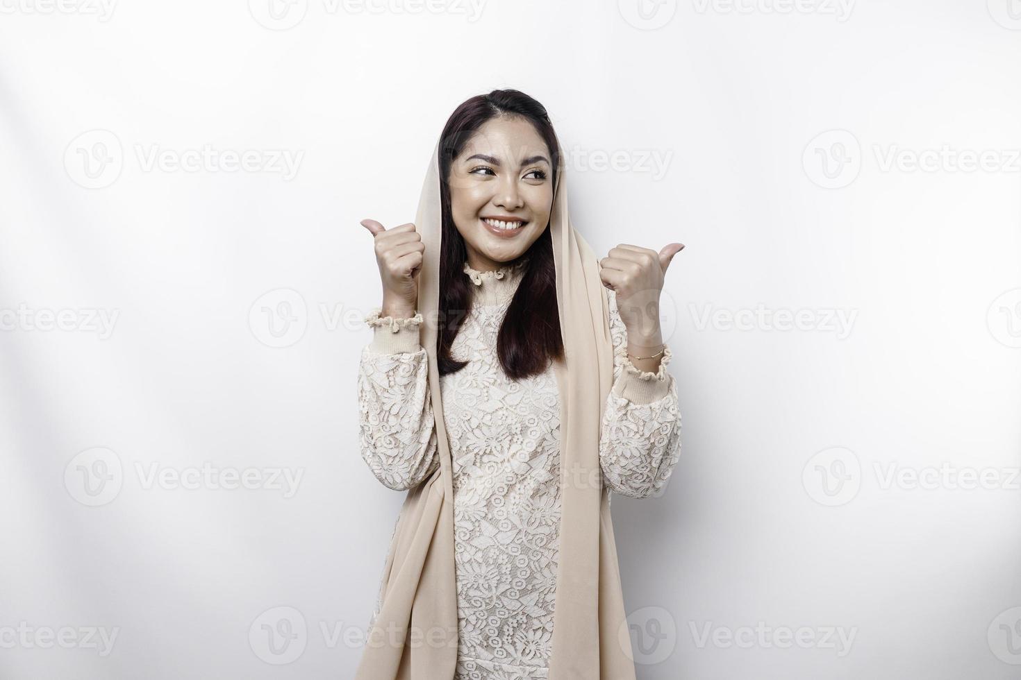 animado ásia muçulmano mulher vestindo uma lenço de cabeça dá polegares acima mão gesto do aprovação, isolado de branco fundo foto