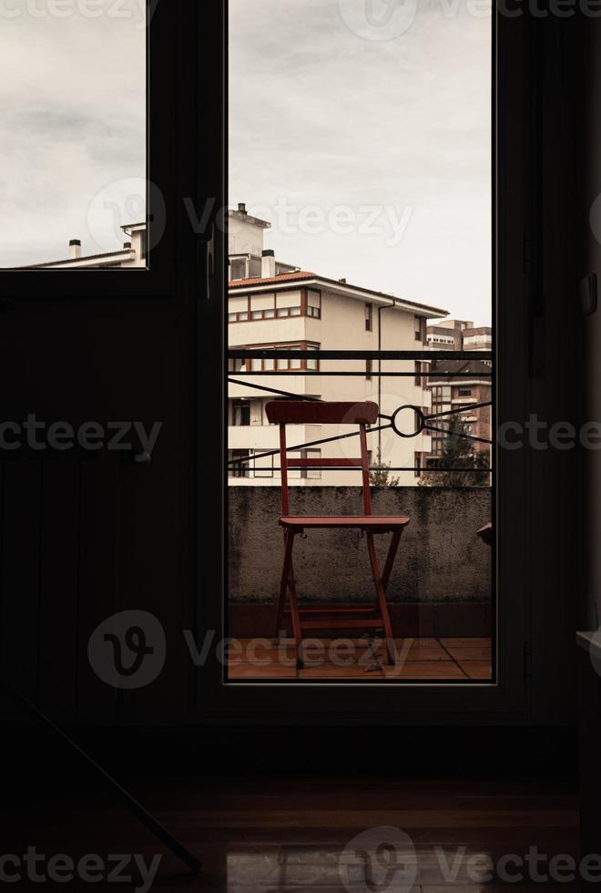 de madeira cadeira em a janela do uma quarto com uma Visão do a cidade. foto