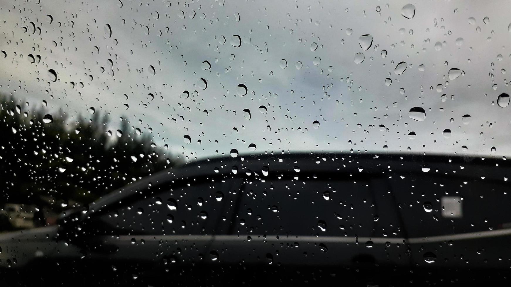 chuva solta em a carro vidro. estrada Visão através carro janela com chuva gotas, dirigindo dentro chuva. foto