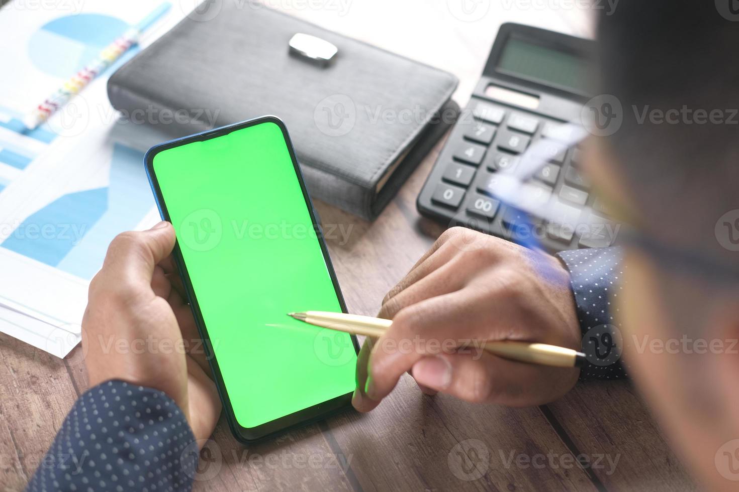 vista traseira da mão do homem usando o telefone inteligente na mesa foto