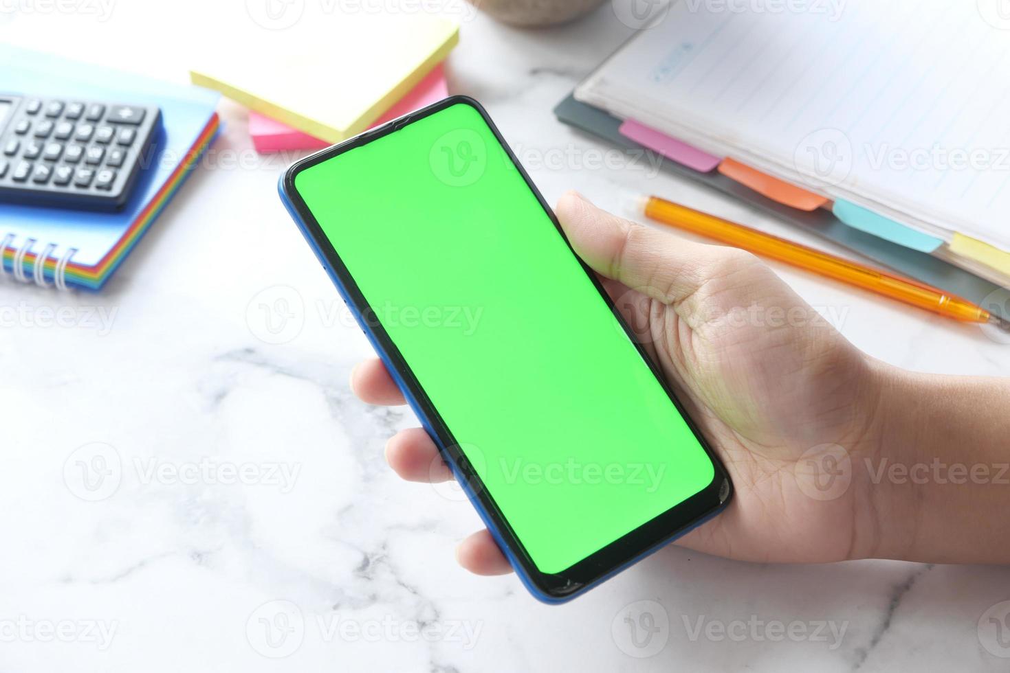 telefone inteligente com tela verde em fundo neutro da mesa foto