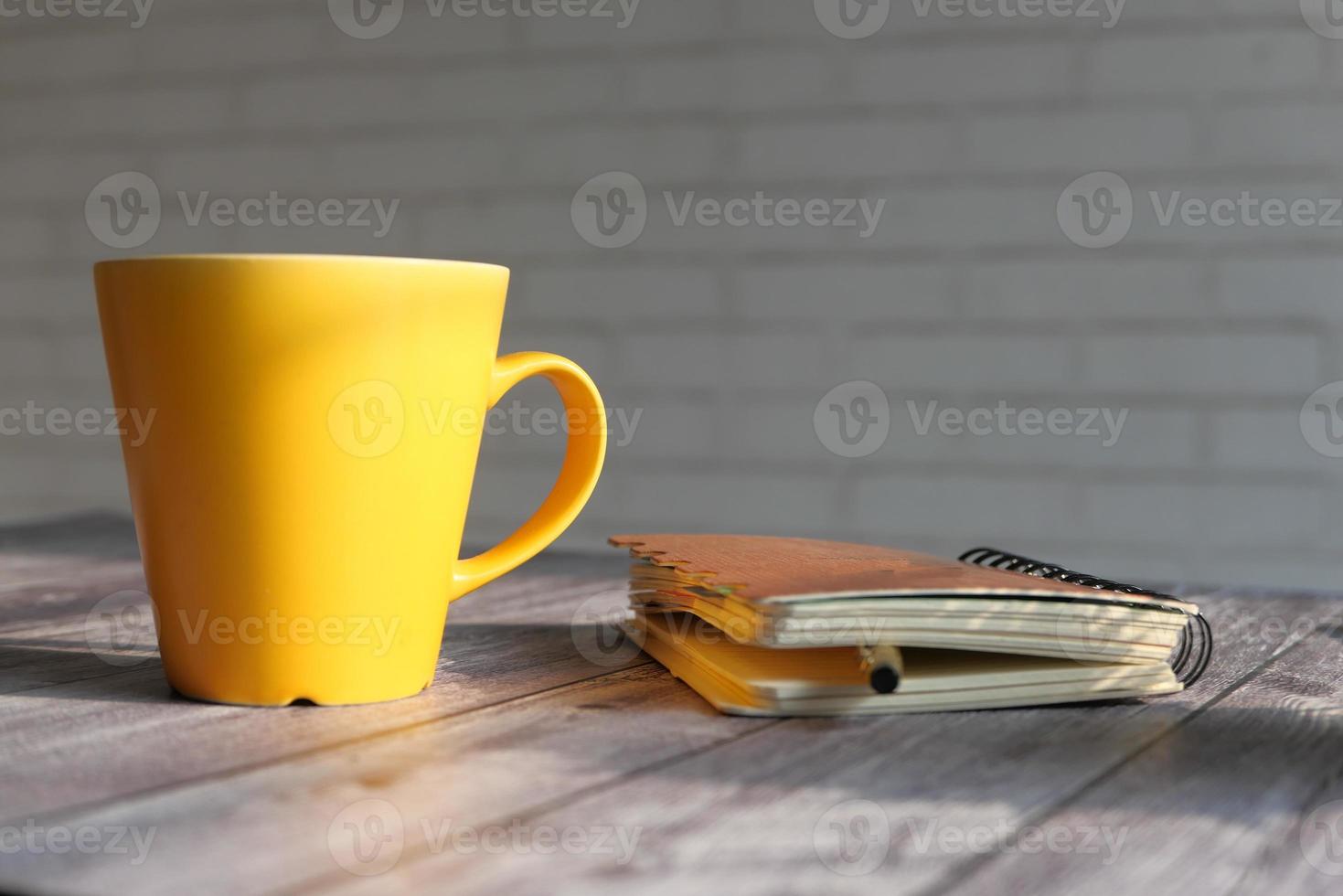 caneca amarela em uma mesa com um caderno foto