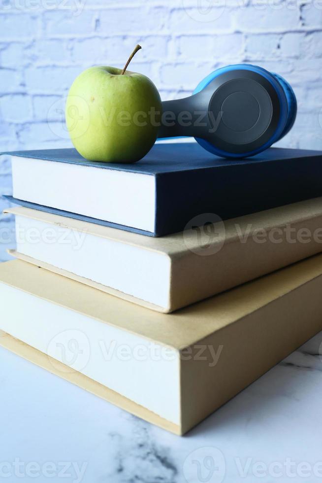 pilha de livros, apple e fones de ouvido na mesa foto