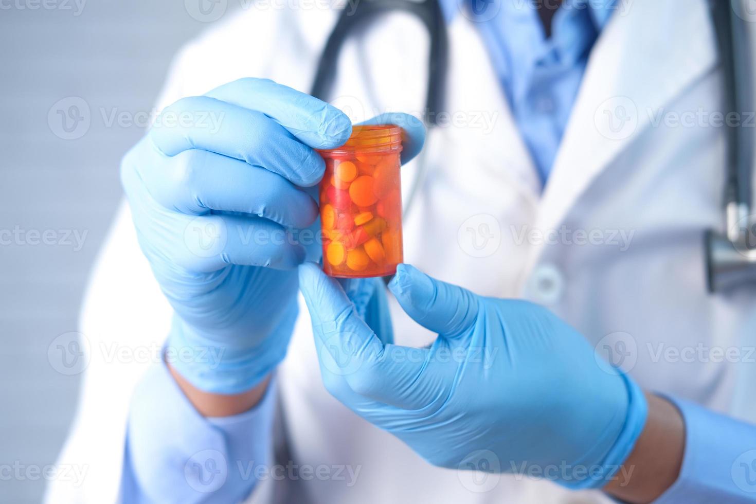 médico segurando um frasco de comprimido de laranja foto