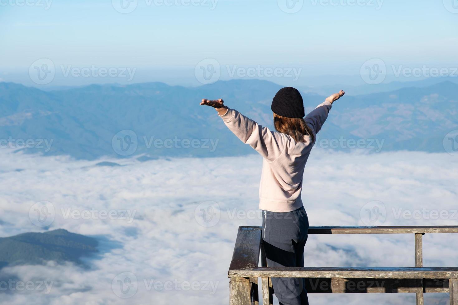 feliz mulher em a nascer do sol dentro natureza com aberto mãos, liberdade estilo de vida, montanha e nuvens plano de fundo, asiático jovem adulto. foto