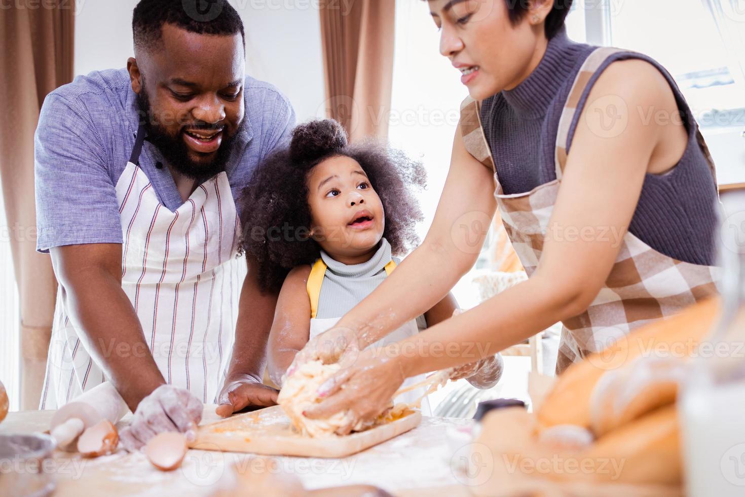 feliz africano americano família apreciar juntos enquanto preparar a farinha para fazer biscoitos às casa foto