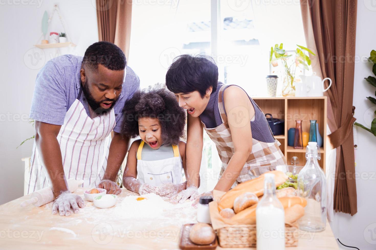 feliz africano americano família apreciar juntos enquanto preparar a farinha para fazer biscoitos às casa foto