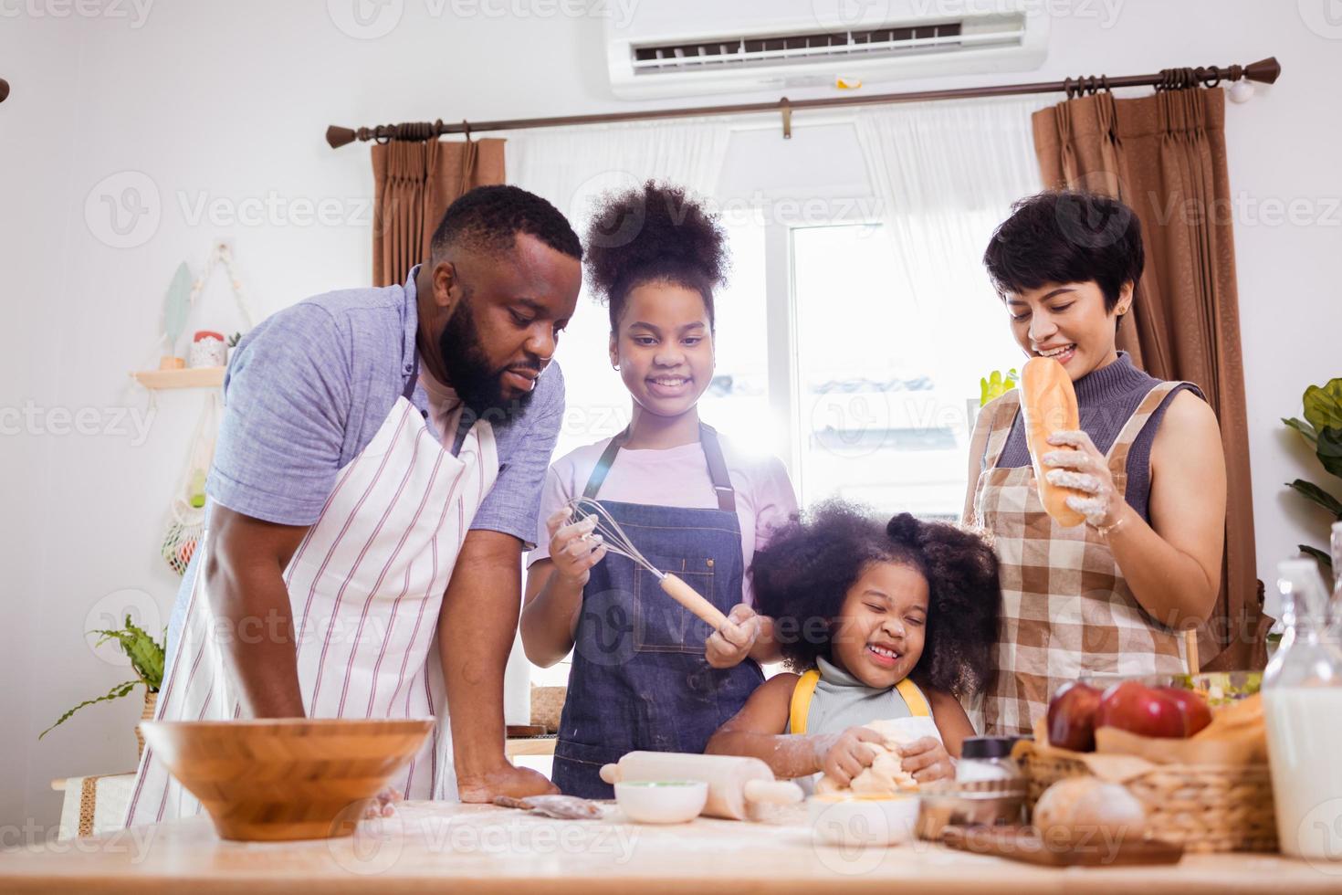 feliz africano americano família apreciar juntos enquanto preparar a farinha para fazer biscoitos às casa foto