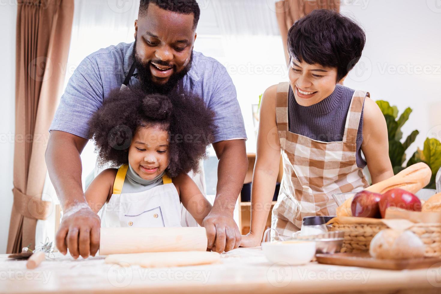 feliz africano americano família apreciar juntos enquanto preparar a farinha para fazer biscoitos às casa foto