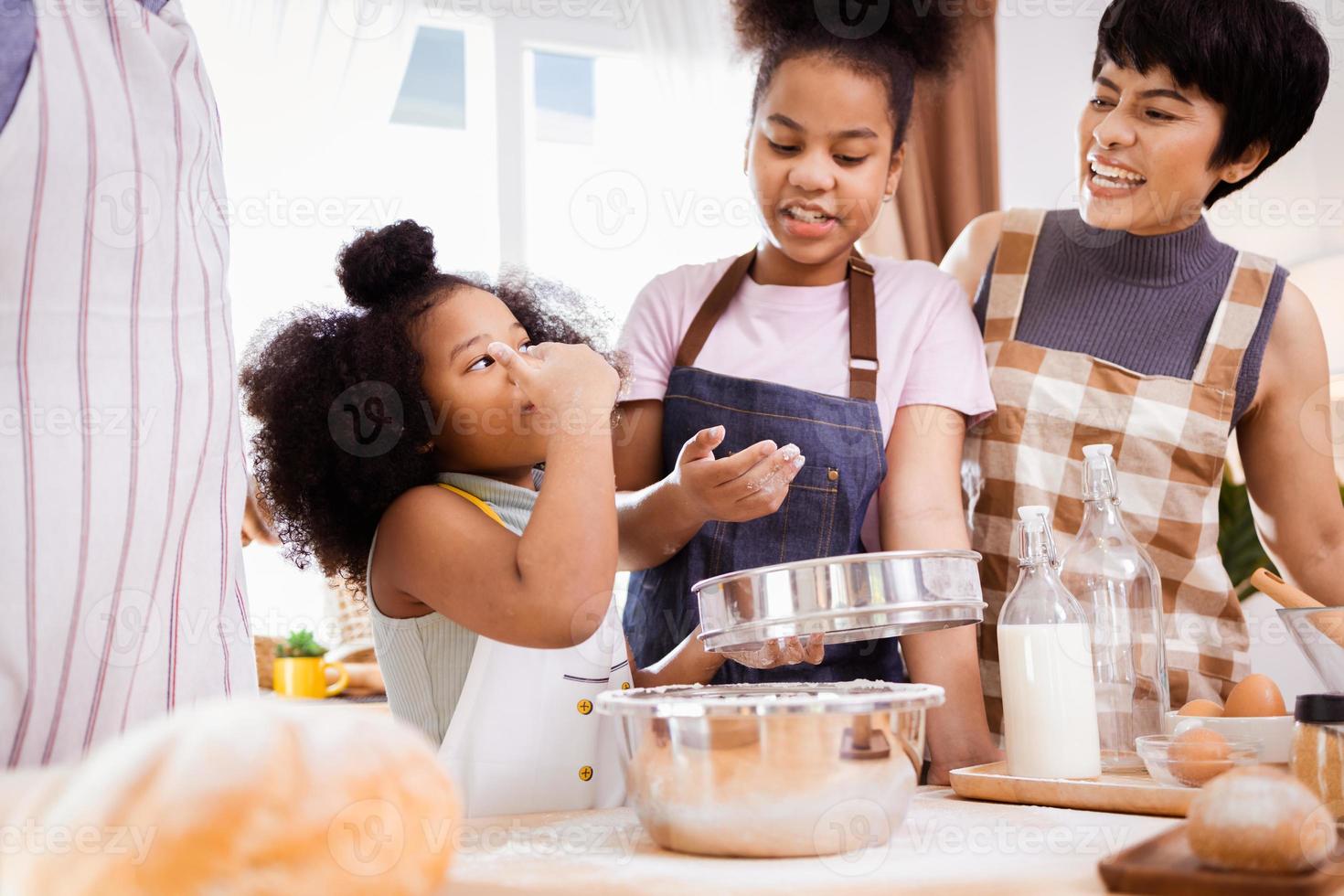 feliz africano americano família apreciar juntos enquanto preparar a farinha para fazer biscoitos às casa foto