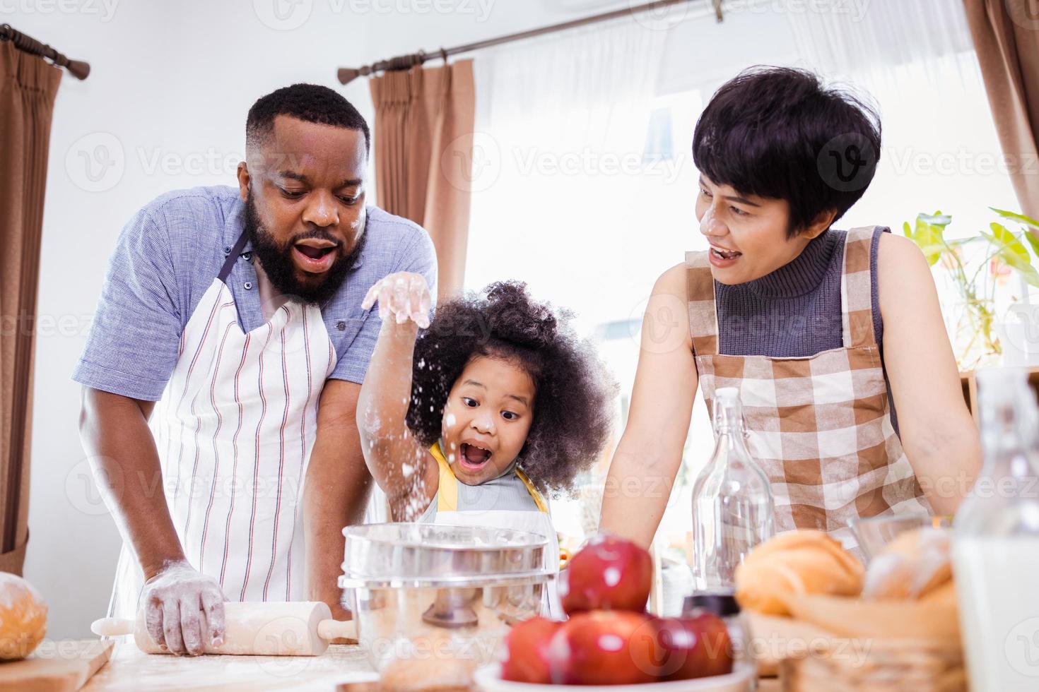 feliz africano americano família apreciar juntos enquanto preparar a farinha para fazer biscoitos às casa foto