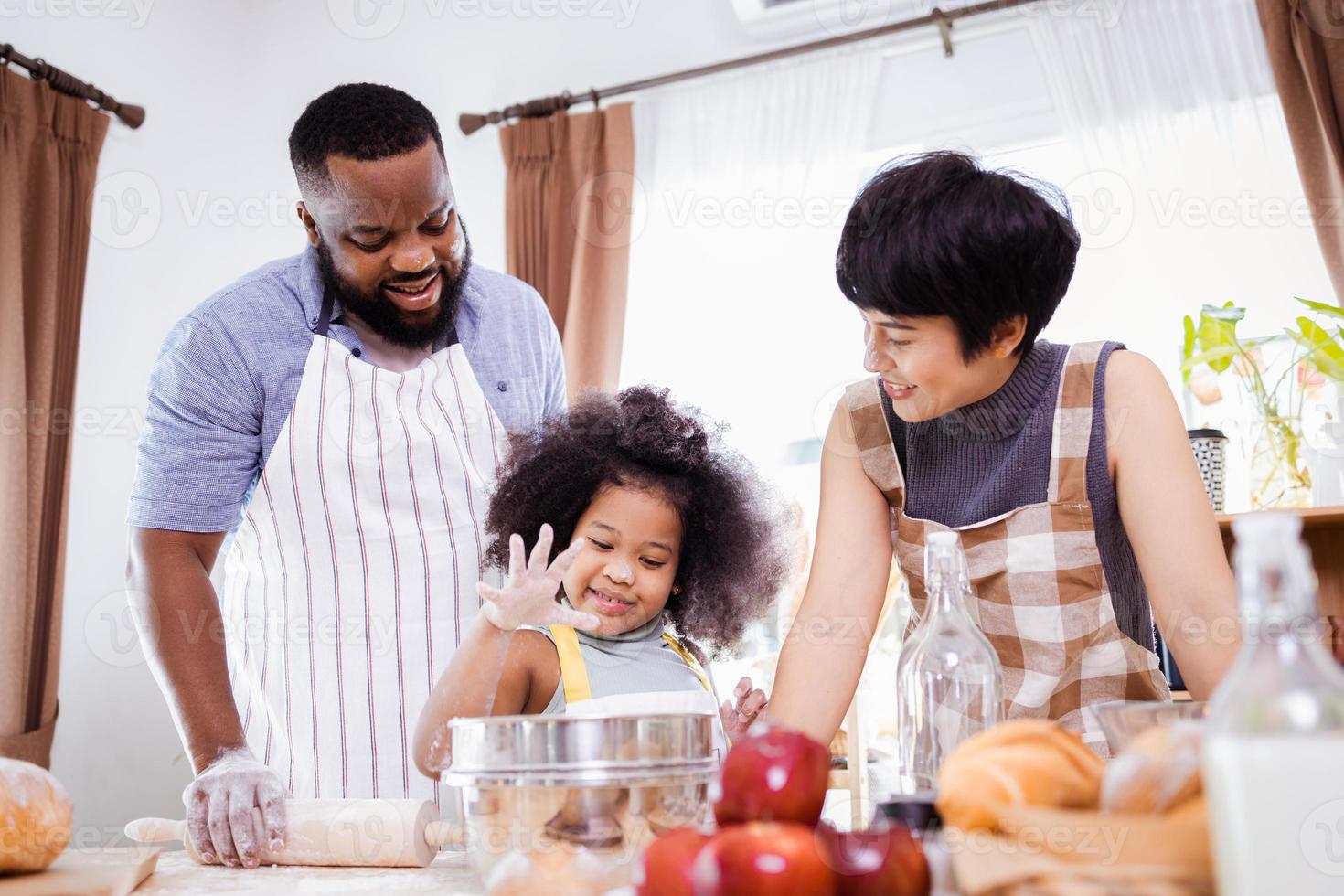 feliz africano americano família apreciar juntos enquanto preparar a farinha para fazer biscoitos às casa foto