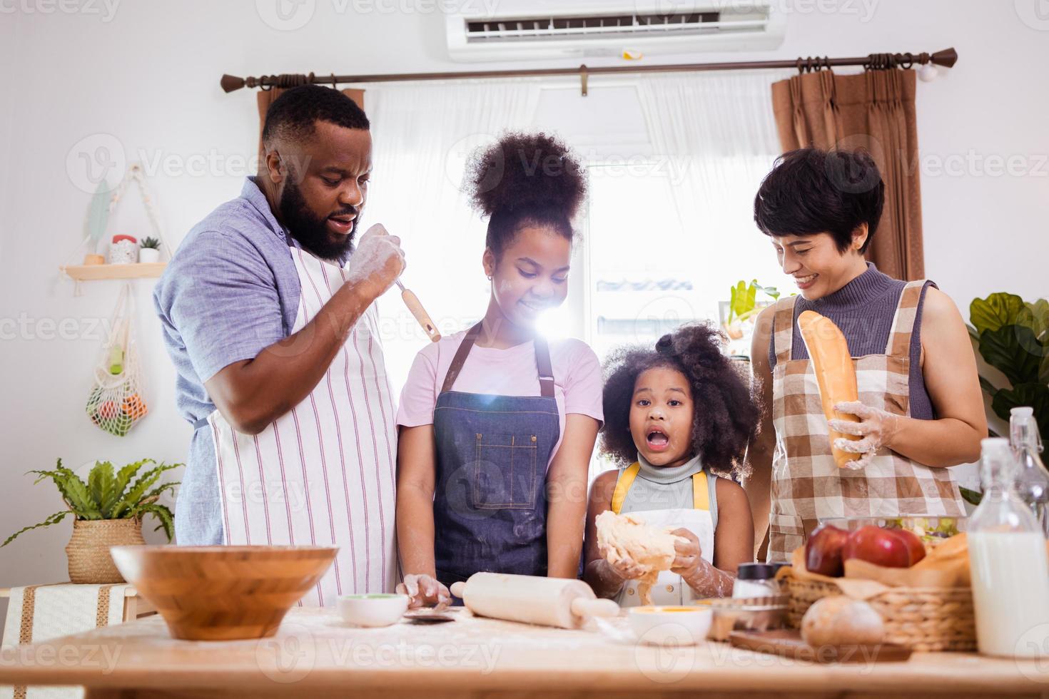 feliz africano americano família apreciar juntos enquanto preparar a farinha para fazer biscoitos às casa foto