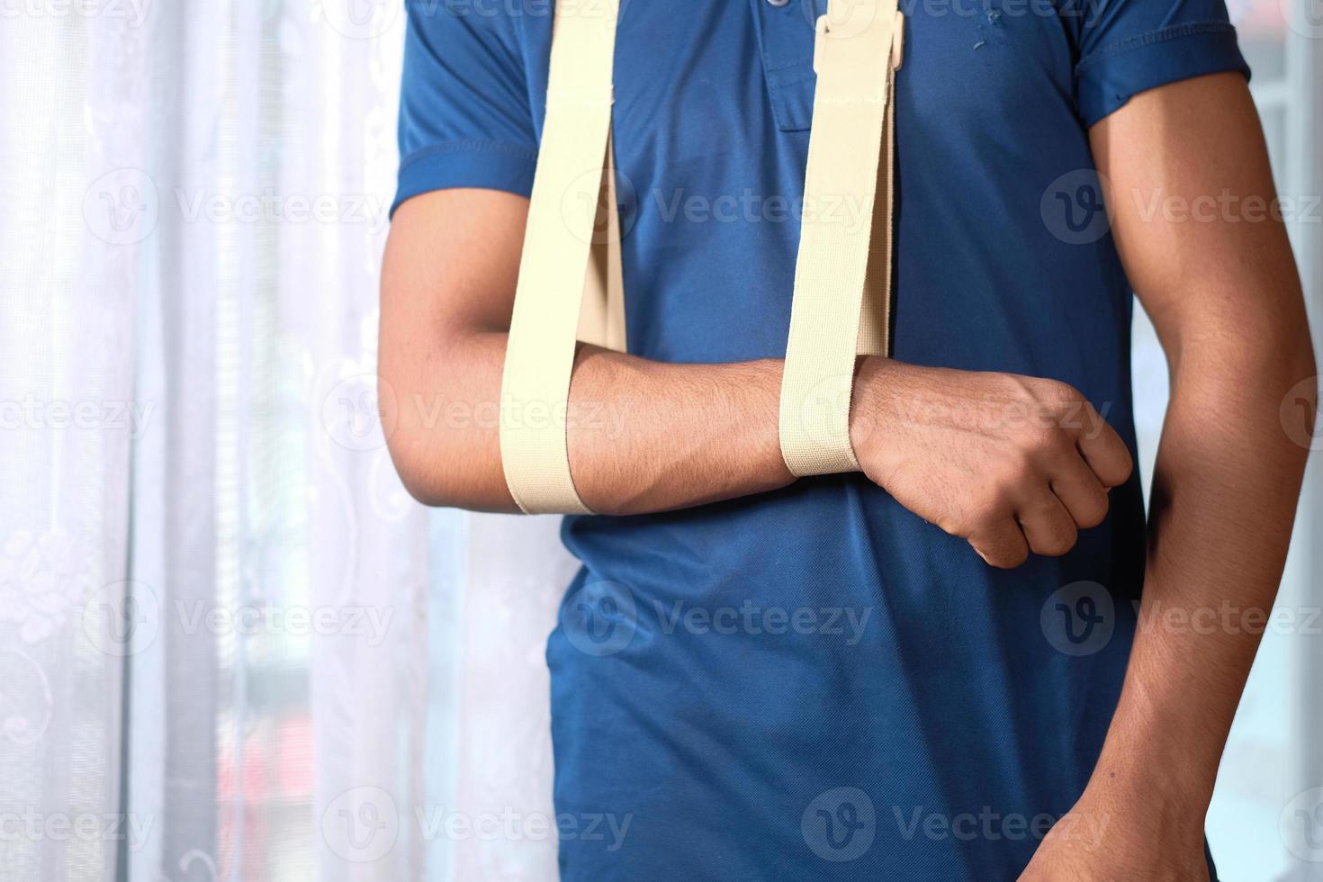 homem de camisa azul usando tipóia de braço foto