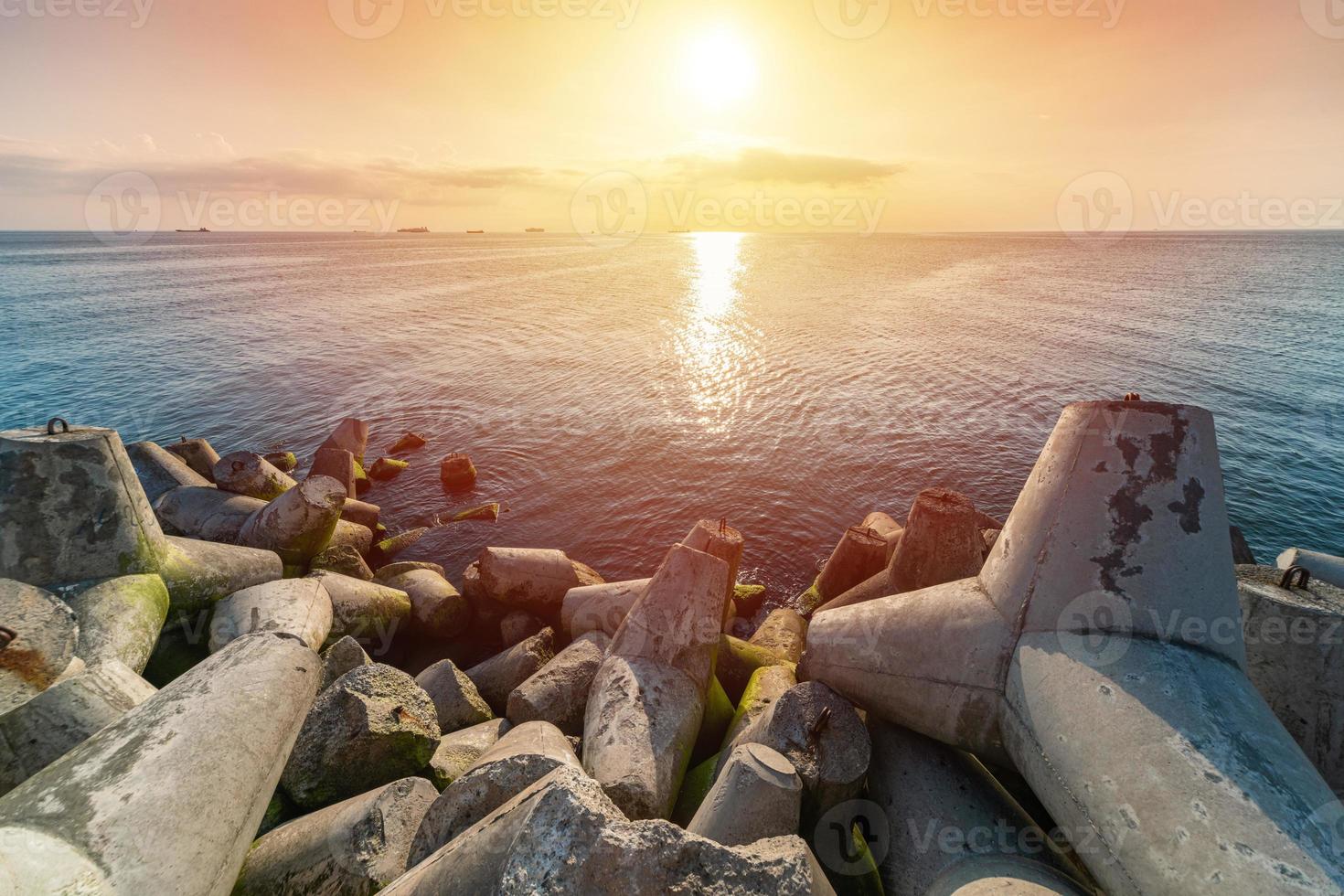 bela paisagem do sol. sonhos de viagem e motivação. tetrápodes de quebra-mares na costa do cais. navios de carga no horizonte. foto