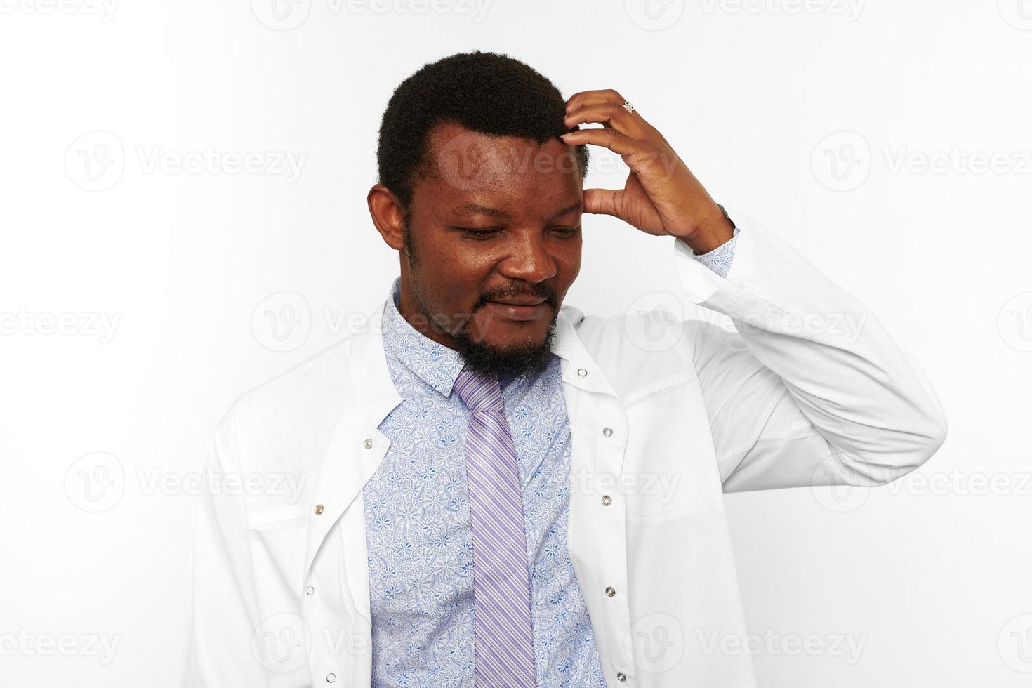 médico preto confuso com barba pequena na camisa brilhante de roupão branco isolado no fundo branco foto