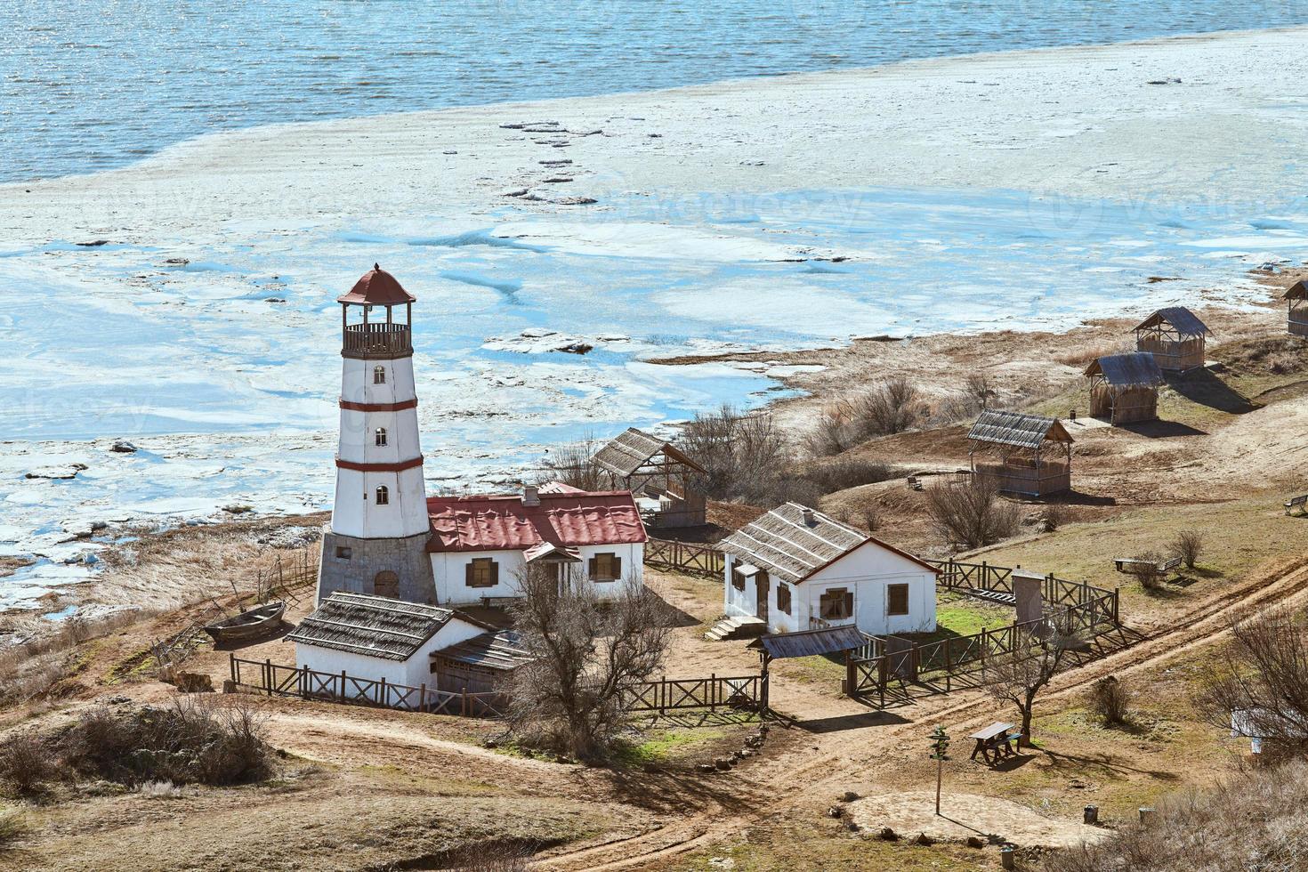 lindo farol vermelho branco com casas de serviços agrícolas em merzhanovo, rostov na região de don russo foto