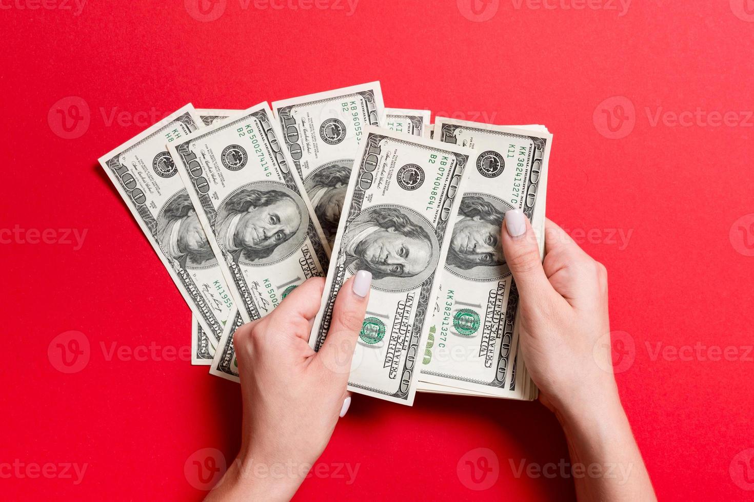topo Visão do fêmea mãos contando dinheiro. 1 cem dólar notas em colorida fundo. salário conceito. suborno conceito foto