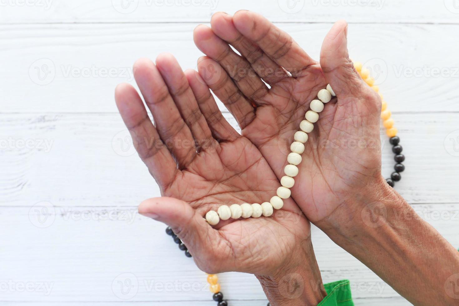 mãos de mulher segurando contas de oração foto