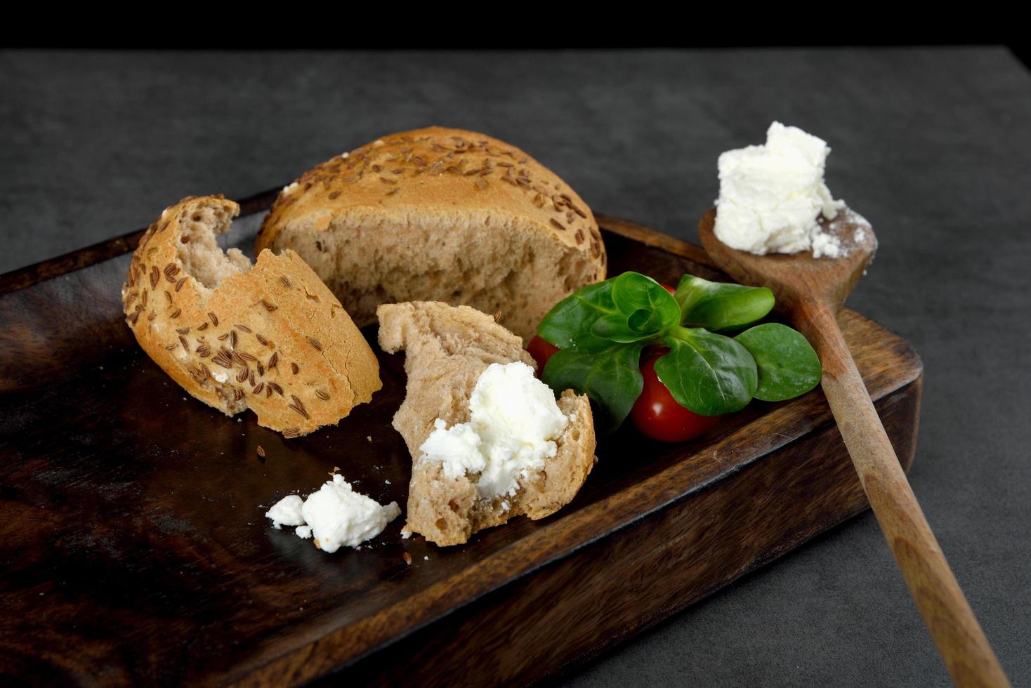 cream cheese no café da manhã, tomates e bagels de grãos em uma superfície cinza foto