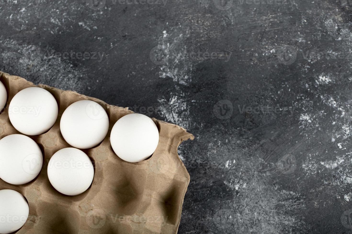 Ovos de galinha crus em uma caixa de ovos em um fundo de mármore foto