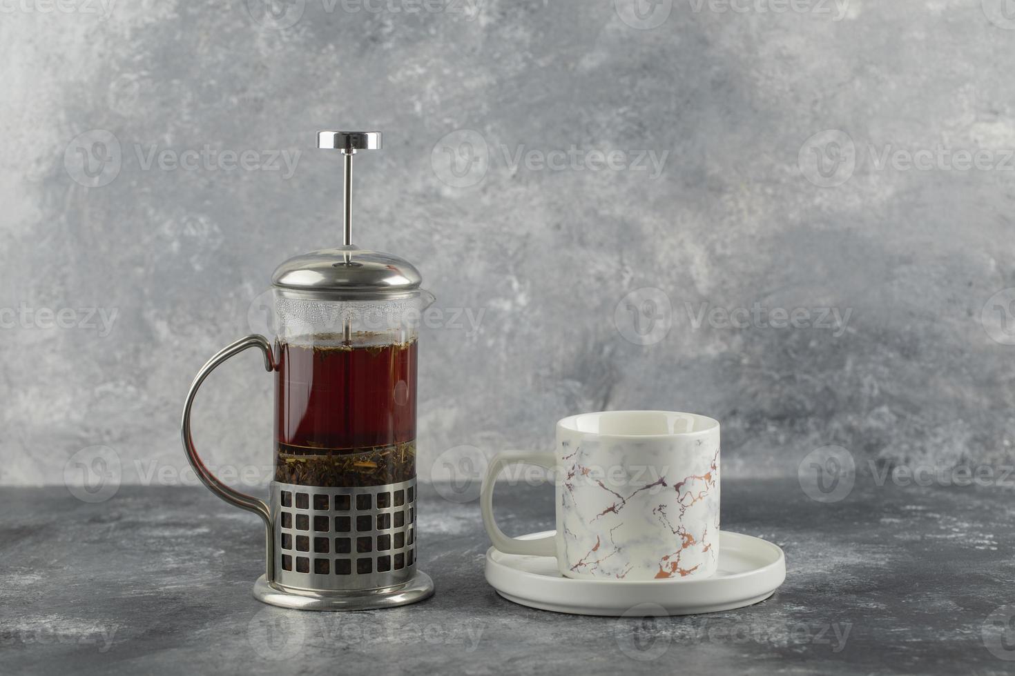 um copo de cerâmica branca com um bule de chá em um fundo de mármore foto
