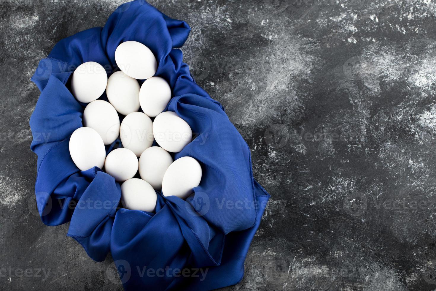 ovos de galinha crus brancos com uma toalha de mesa azul foto