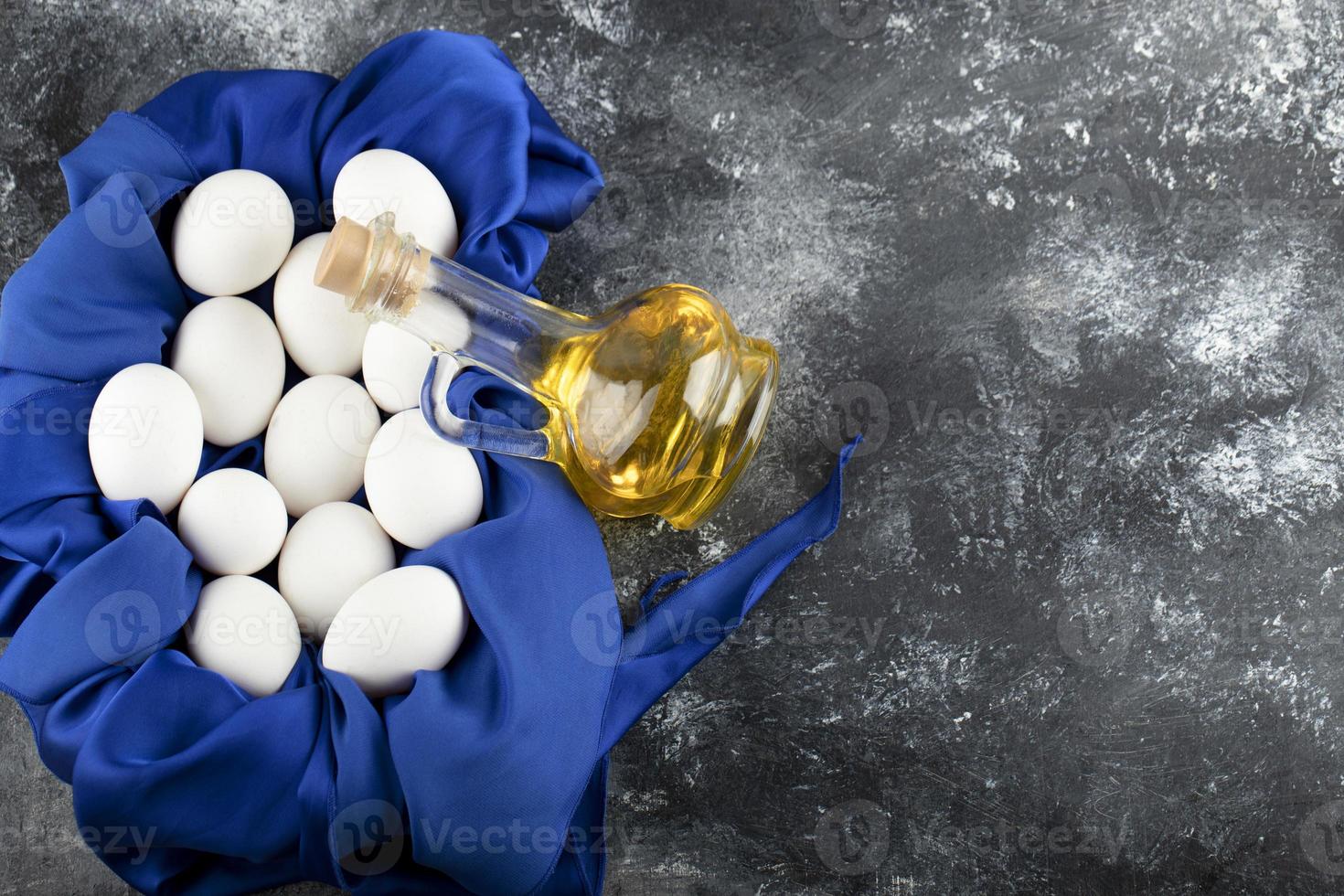 ovos de galinha crus brancos com uma garrafa de vidro de óleo foto