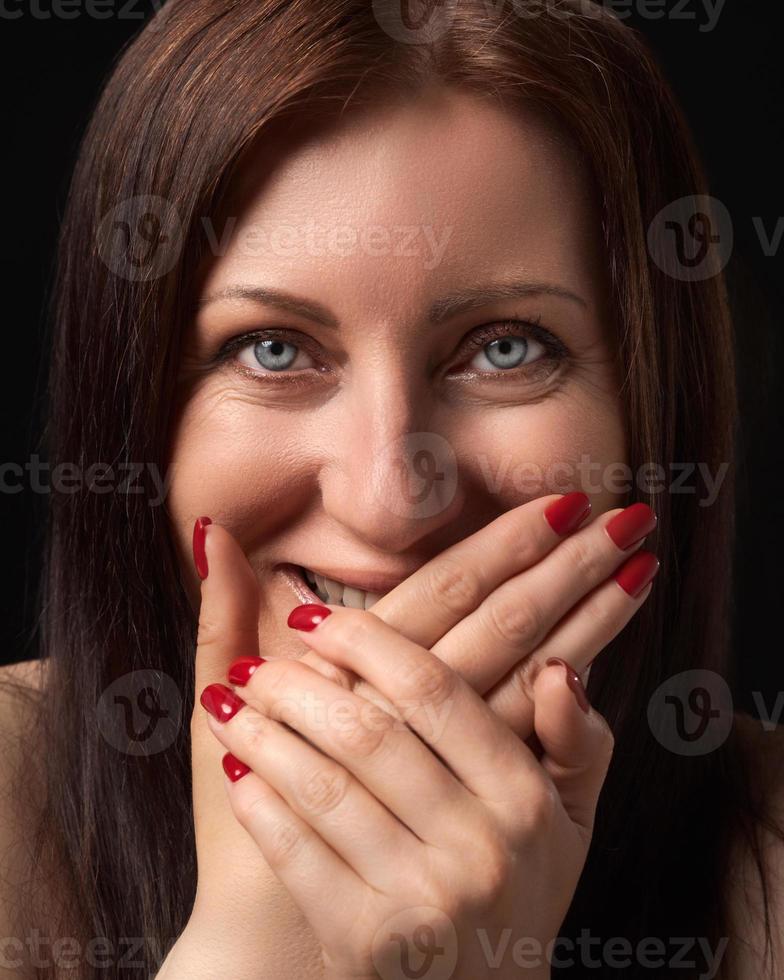 alegre mulher rindo enquanto cobertura boca com dela mãos e olhando às Câmera. estúdio retrato foto