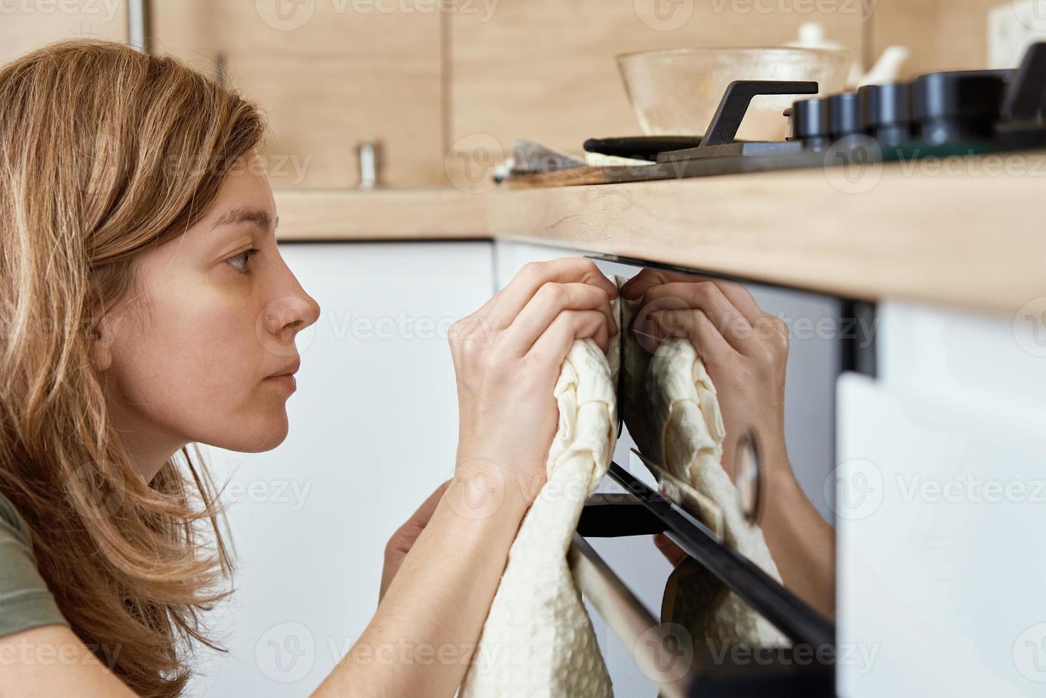 mulher limpeza elétrico forno dentro cozinha foto