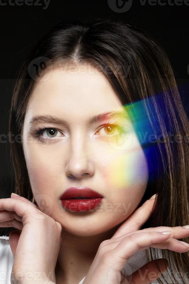 lindo menina modelo com sensual lábios em uma Preto fundo com a ótico arco Iris efeito. foto