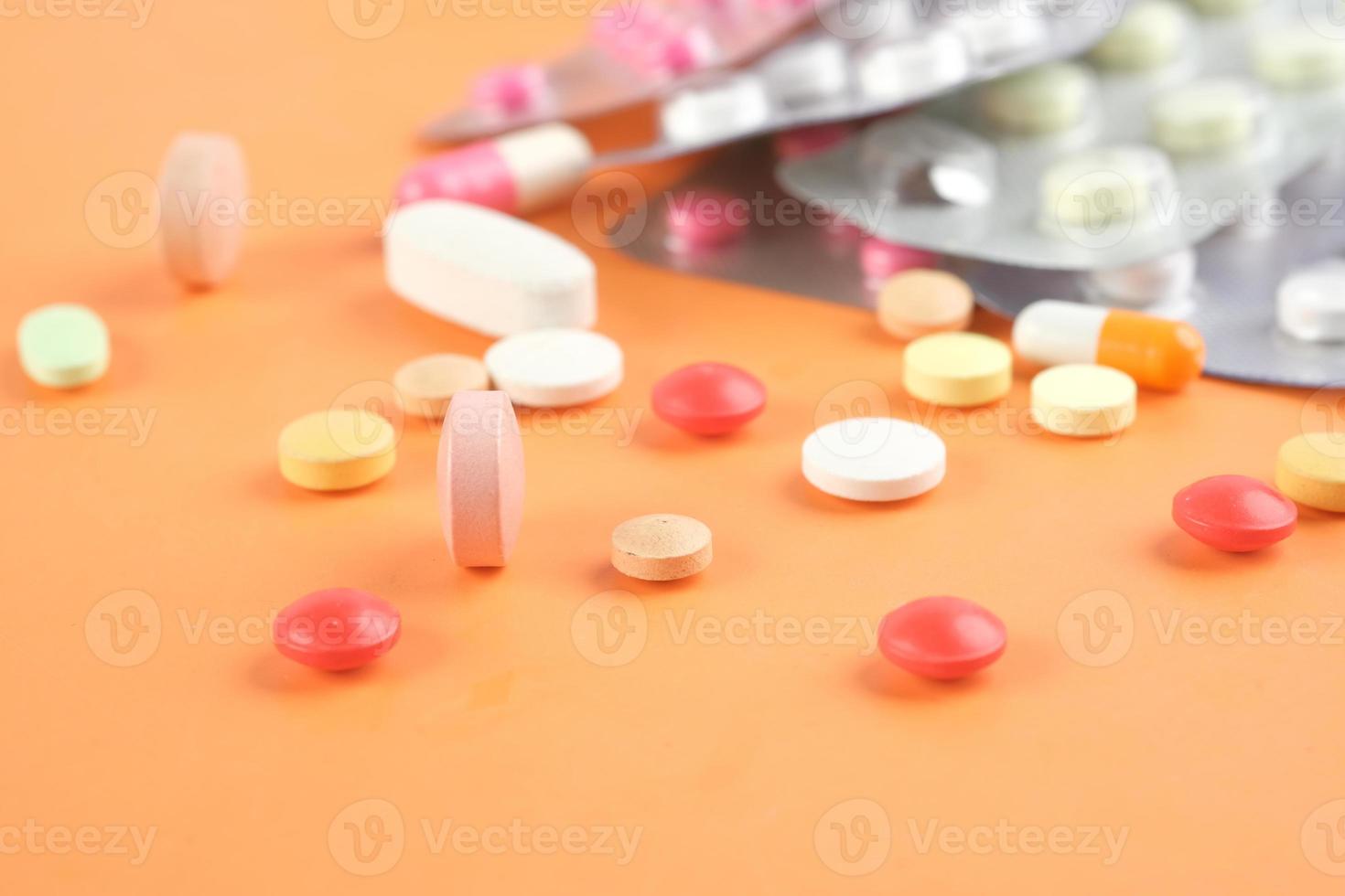 close-up de muitos comprimidos e cápsulas coloridas em fundo laranja foto