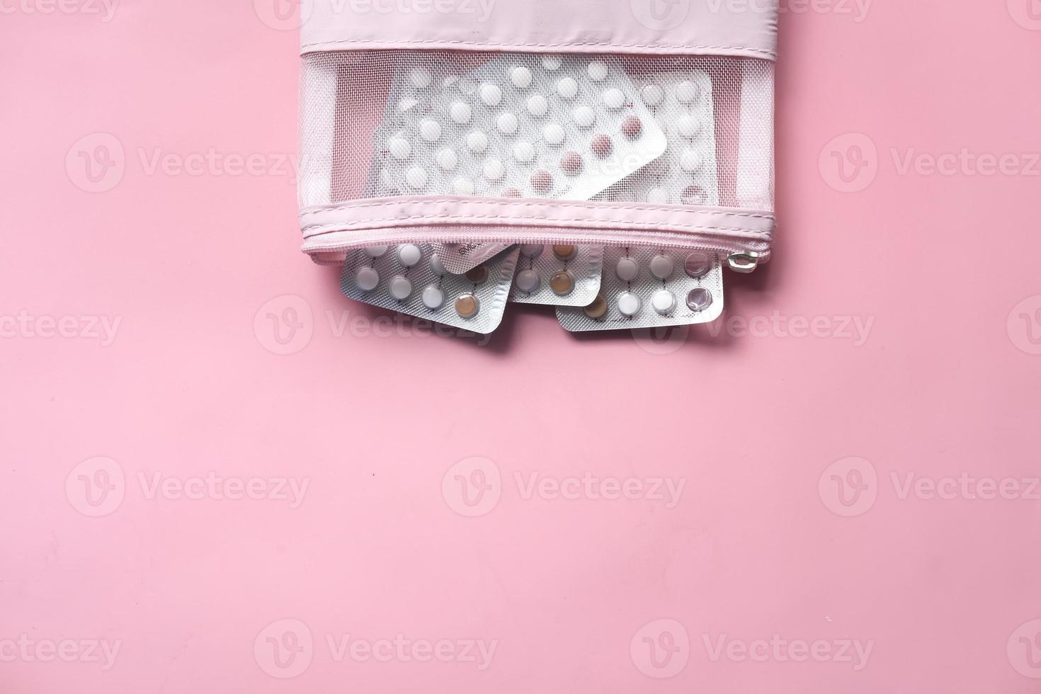 pílulas anticoncepcionais em fundo rosa foto
