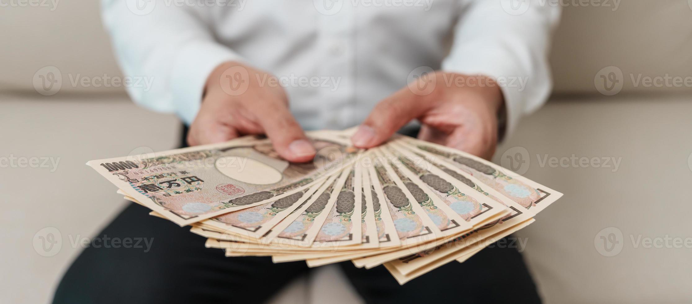 mão de homem segurando a pilha de notas de iene japonês. dinheiro de mil ienes. dinheiro do japão, impostos, economia de recessão, inflação, investimento, finanças e conceitos de pagamento de compras foto