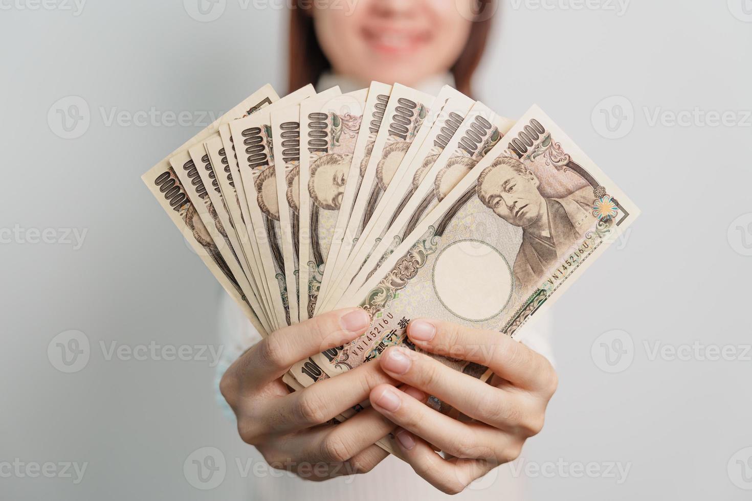 mão de uma mulher segurando a pilha de notas de iene japonês. dinheiro de mil ienes. dinheiro do japão, impostos, economia de recessão, inflação, investimento, finanças e conceitos de pagamento de compras foto