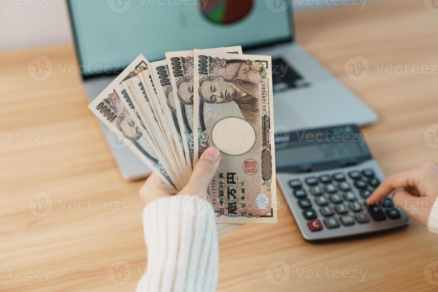 mão de mulher contando notas de iene japonês com calculadora. dinheiro de mil ienes. dinheiro do japão, imposto, economia de recessão, inflação, investimento, finanças, salários e conceitos de pagamento foto