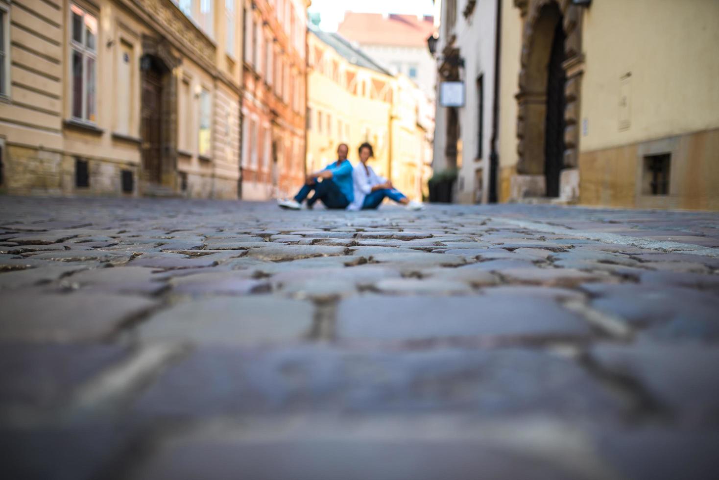 um rapaz e uma rapariga numa velha rua de paralelepípedos na europa foto