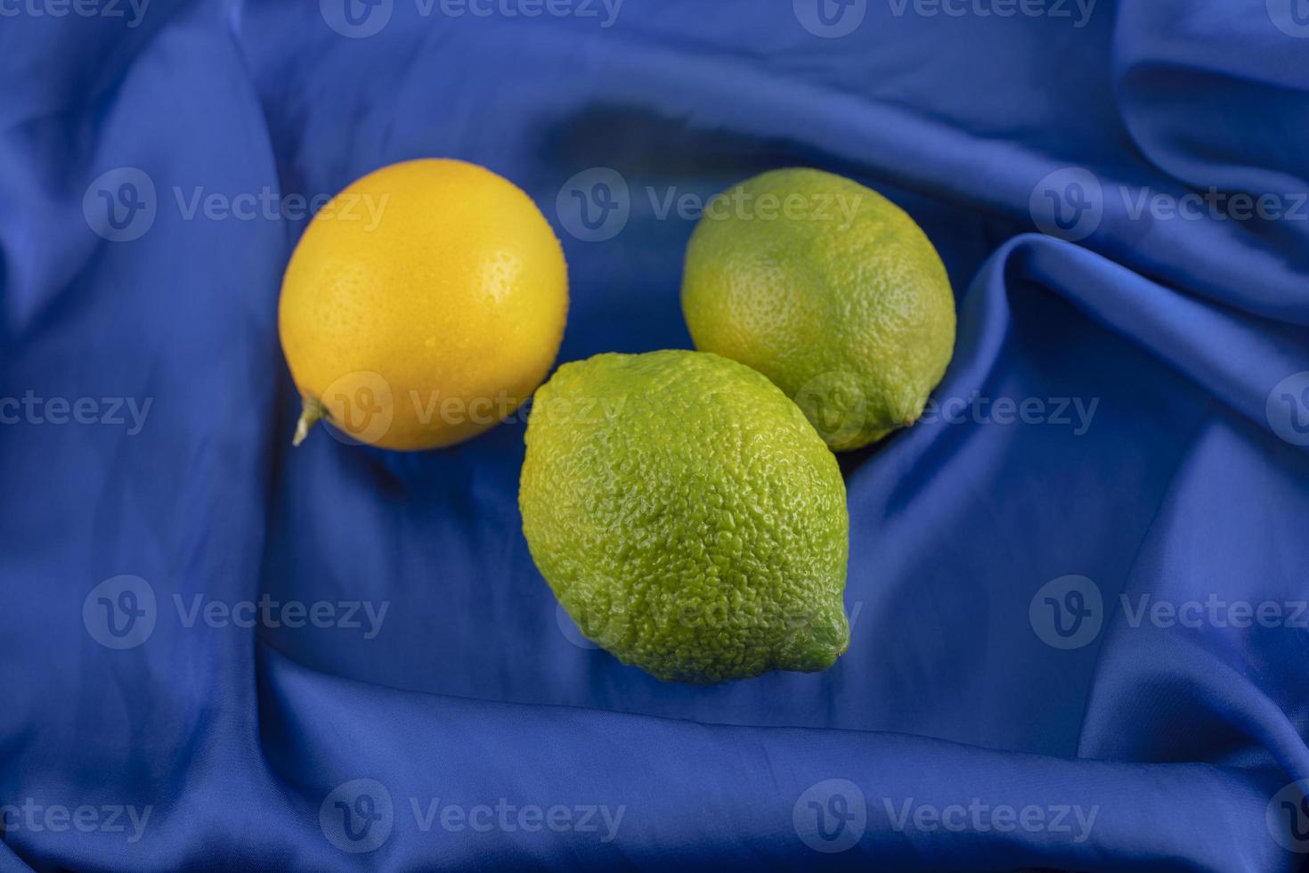 limões amarelos e verdes em uma toalha de mesa azul foto