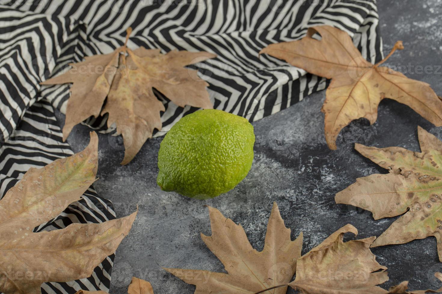 um limão verde maduro com folhas secas foto