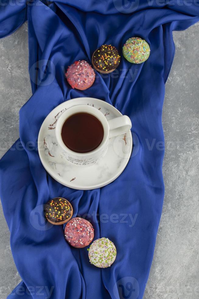 rosquinhas doces coloridas com uma xícara de chá foto