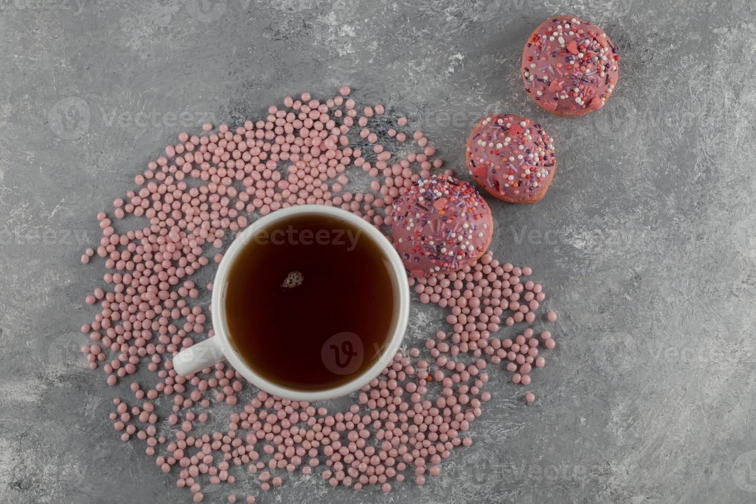 rosquinhas rosadas com uma xícara de chá foto