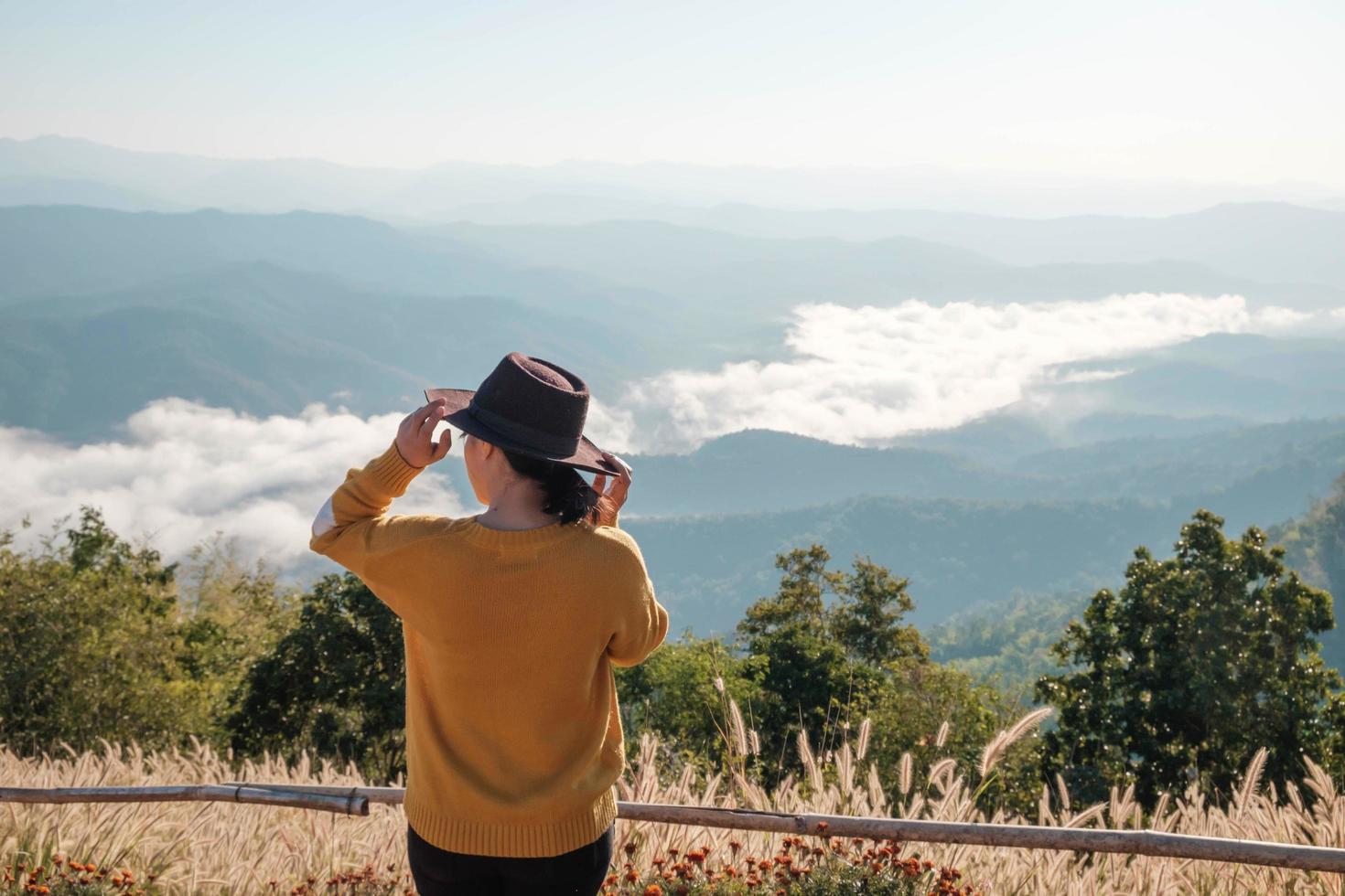 mulher com um chapéu no topo de uma montanha foto