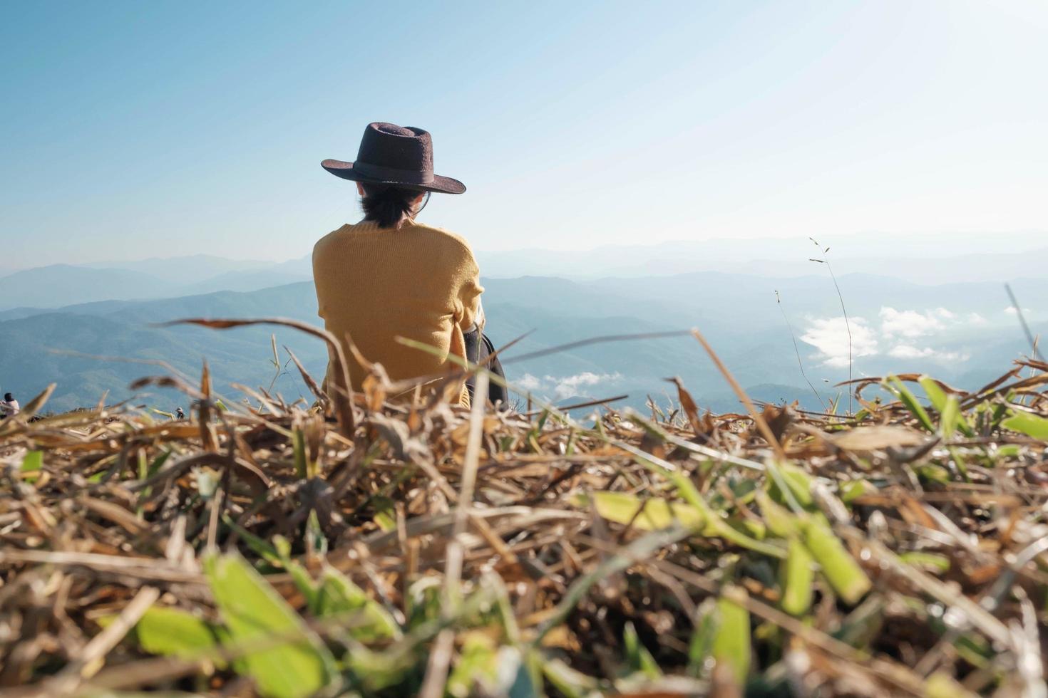 mulher sentada em uma montanha durante o dia foto