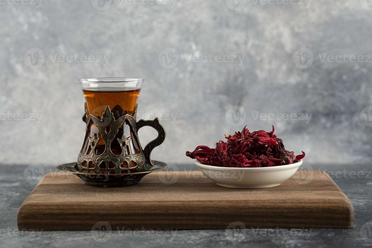 uma xícara de chá quente com flores secas em uma tábua de madeira foto