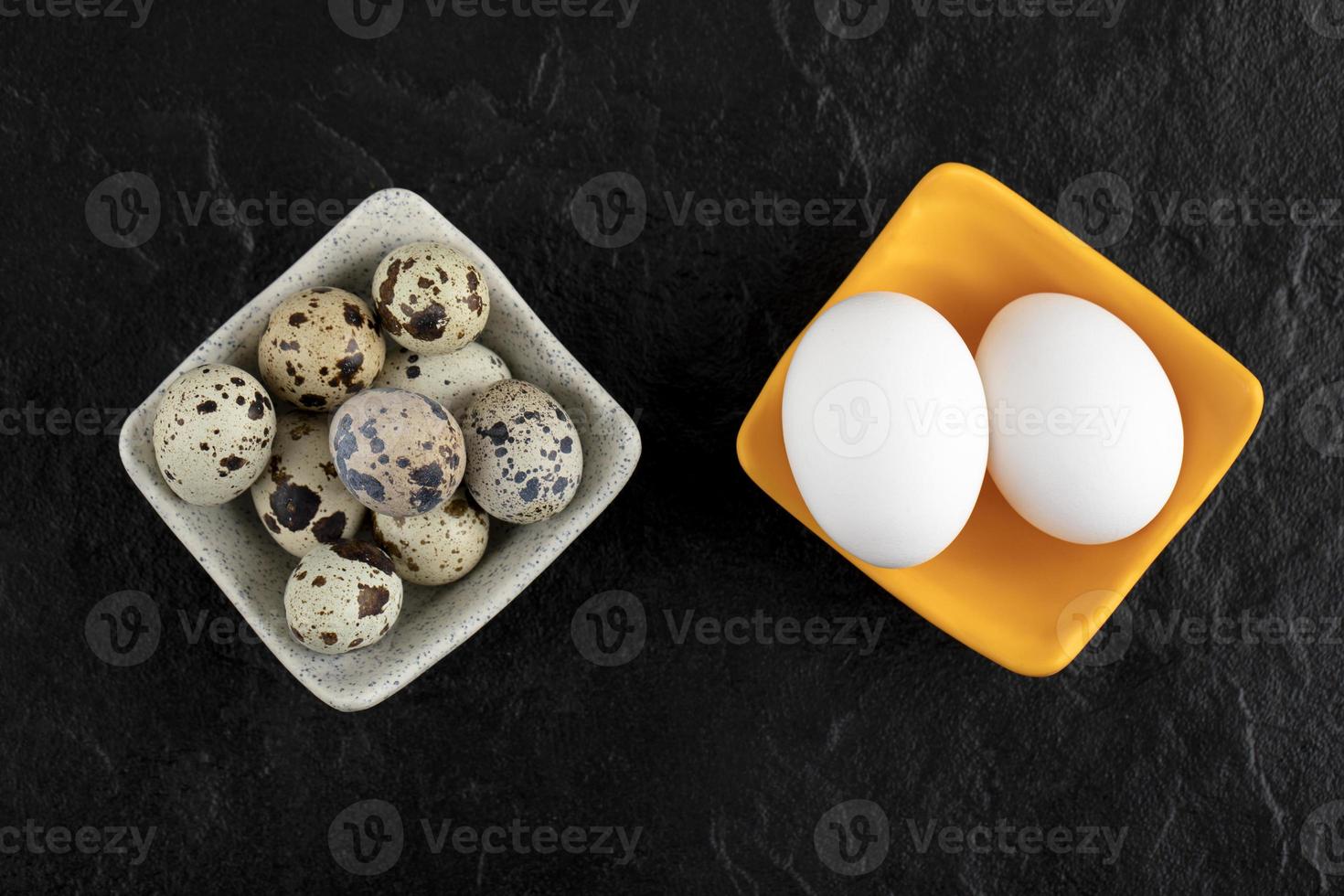 três ovos de codorna e ovos de galinha em um fundo preto foto