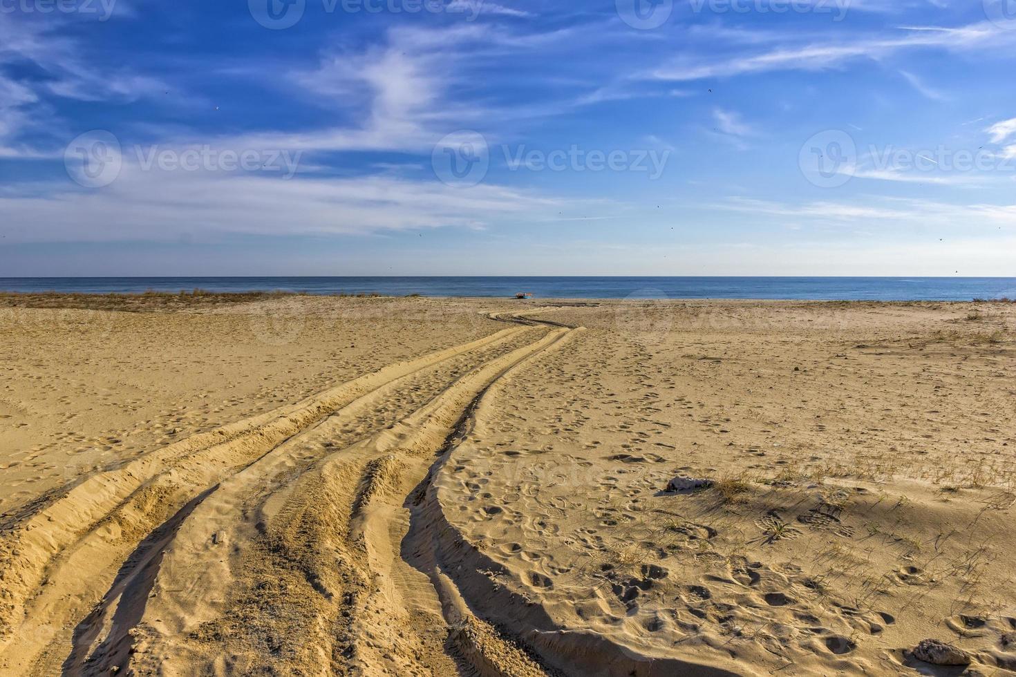 vestígios do carro pneus em a areia do a mar de praia. carro pneus impressões em mar areia durante a dia foto