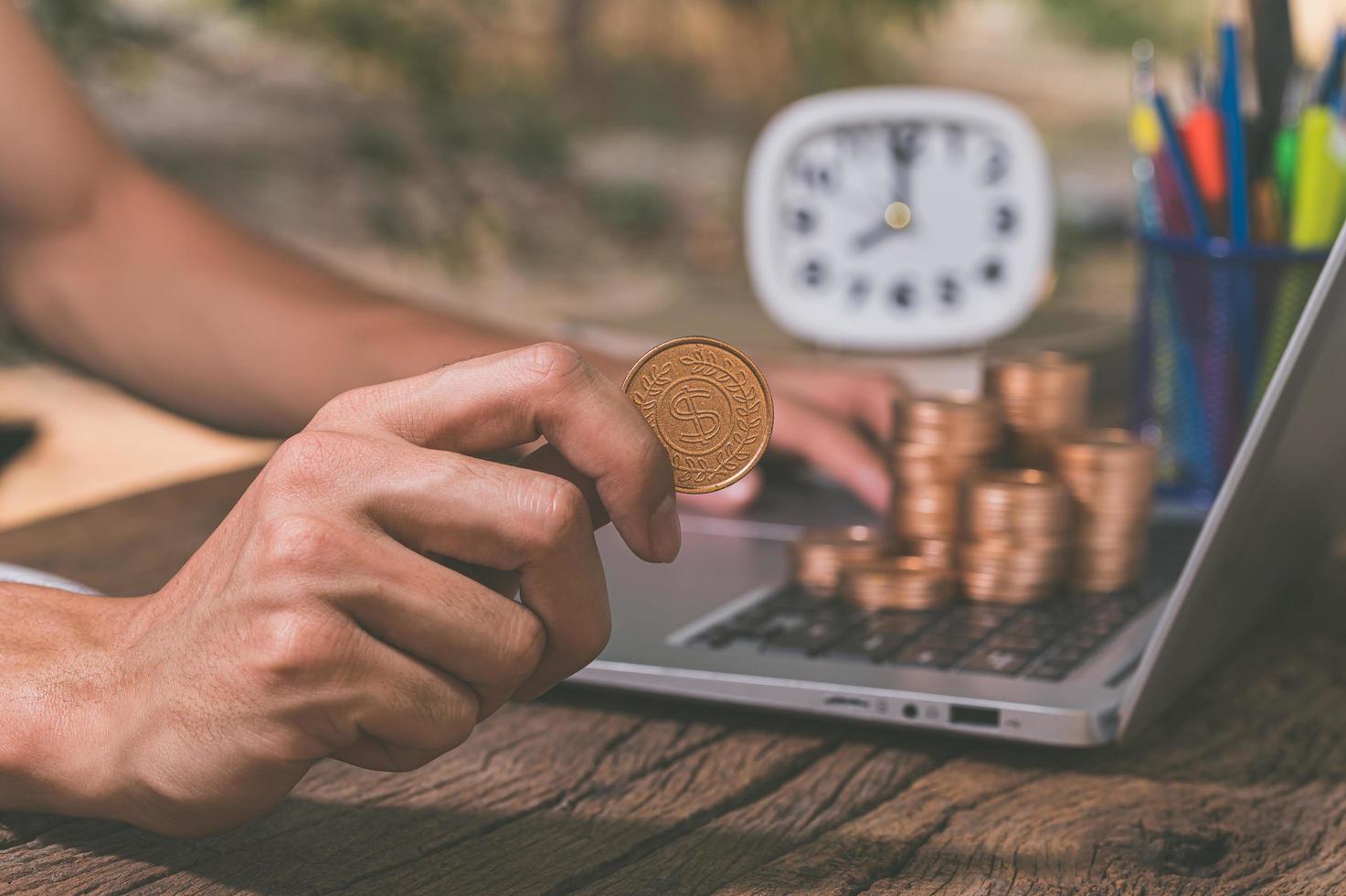 uma pessoa usando um computador com uma pilha de moedas, conceito de ganhar dinheiro online foto