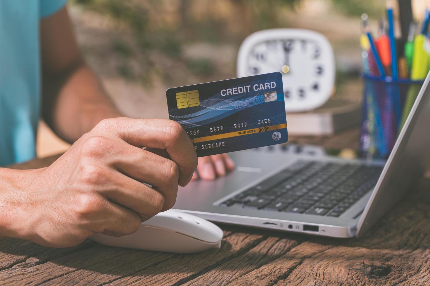 uma pessoa que possui um cartão de crédito para fazer compras online por meio de um notebook foto