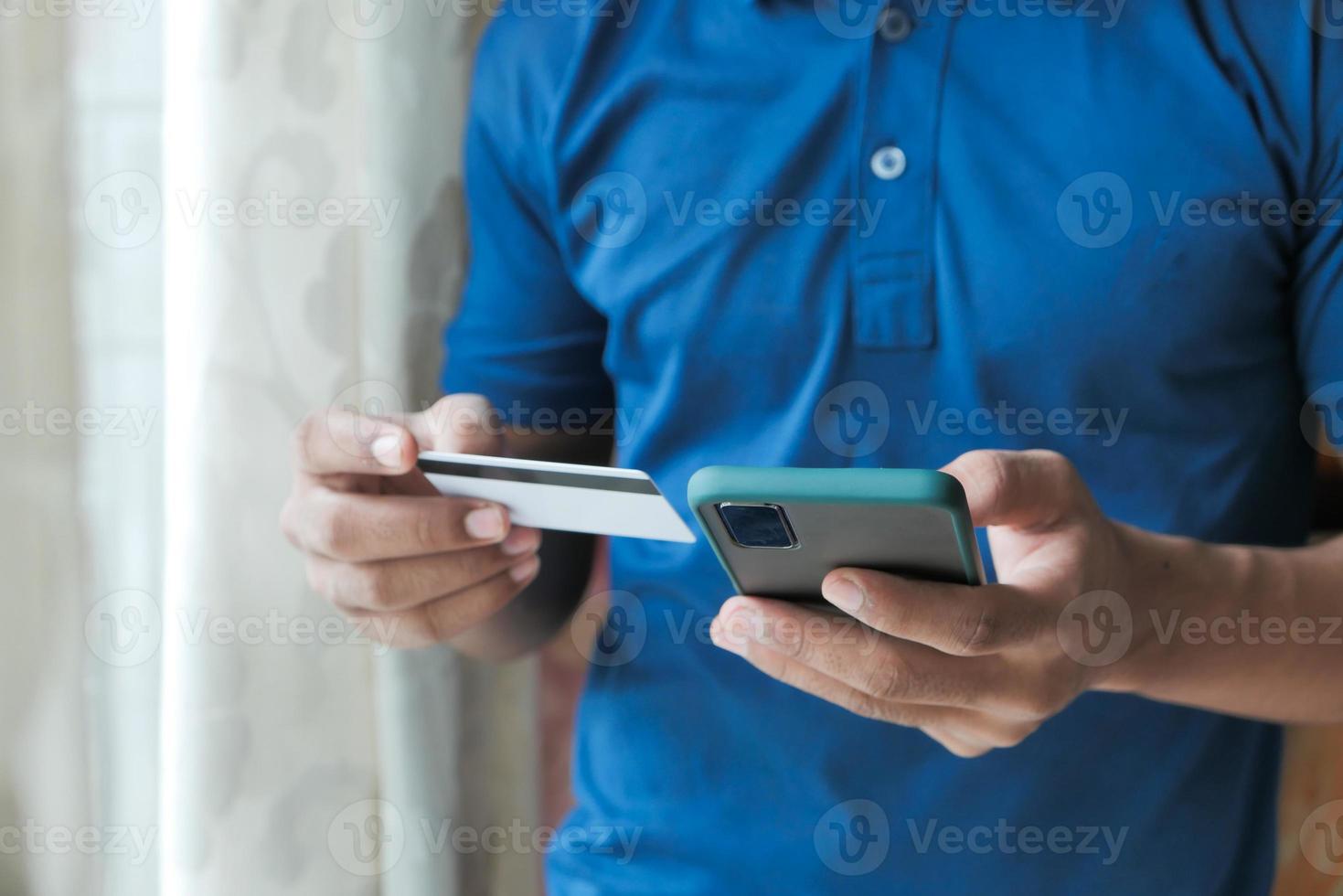 mão do homem segurando um cartão de crédito e usando o smartphone para fazer compras online foto
