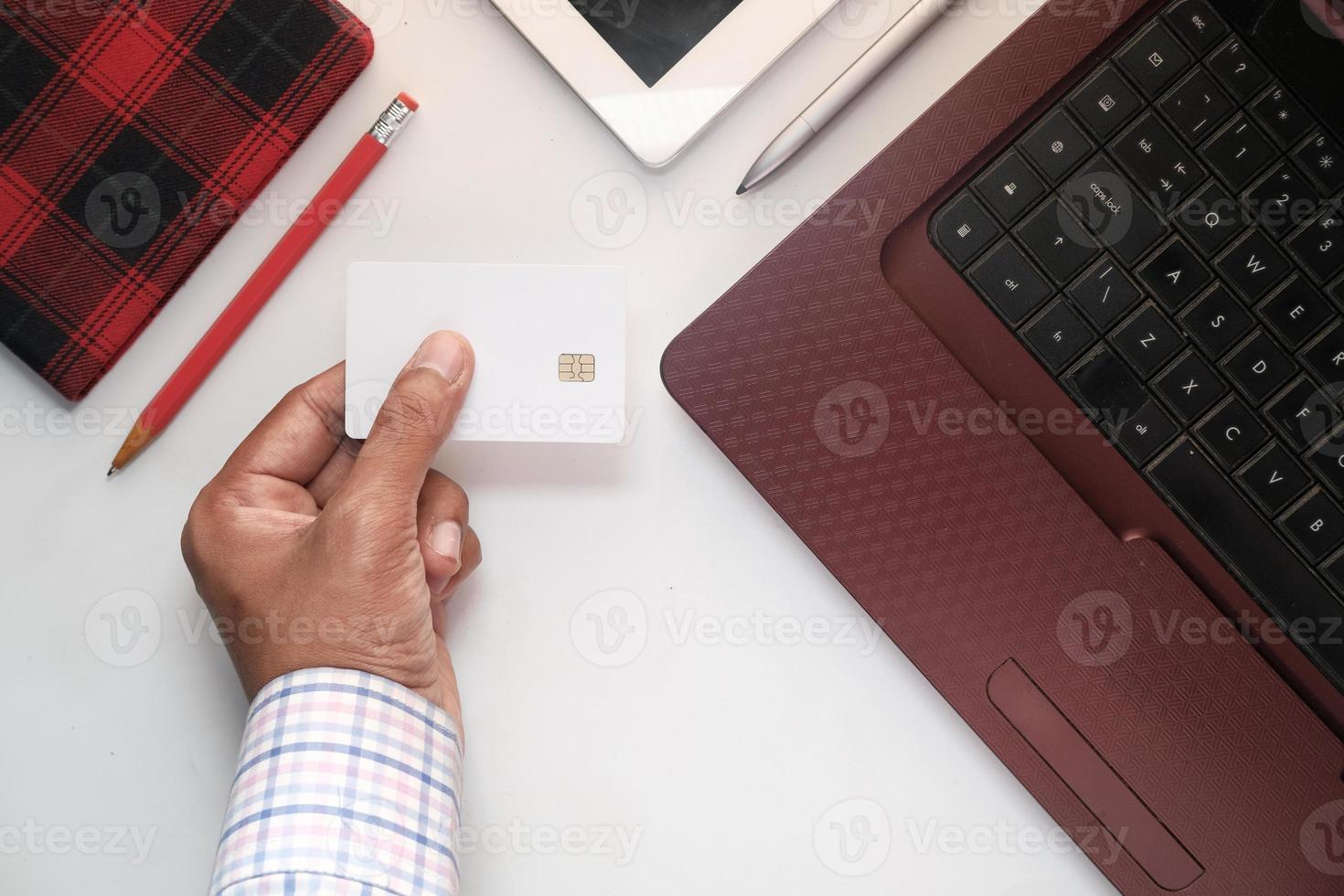 a mão do homem segurando um cartão de crédito branco foto